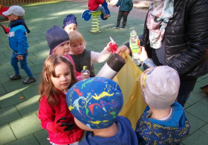 Dzieci podczas zbierania i wrzucania śmieci do odpowiednich worków.